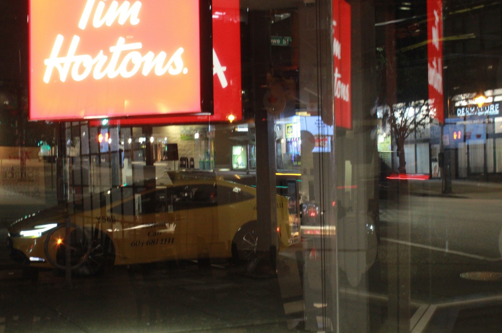 Tim Hortons storefront reflected with a taxi and city lights at night — Joe Passage