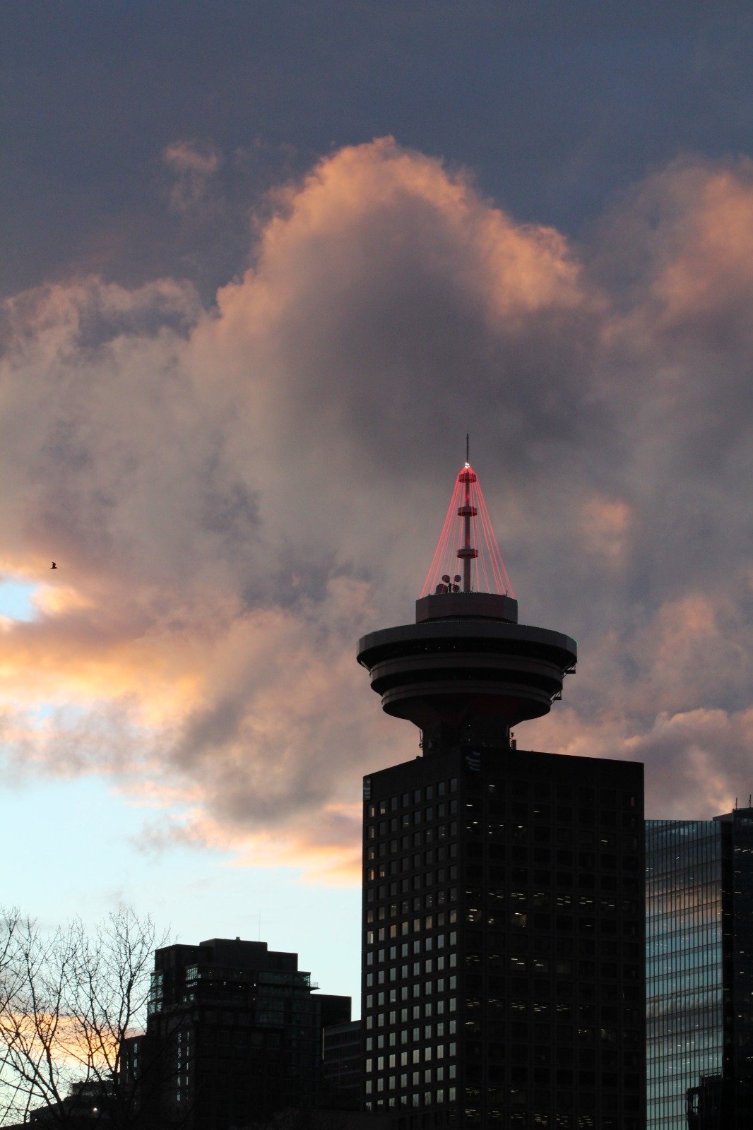 City tower beneath dramatic clouds at sunset