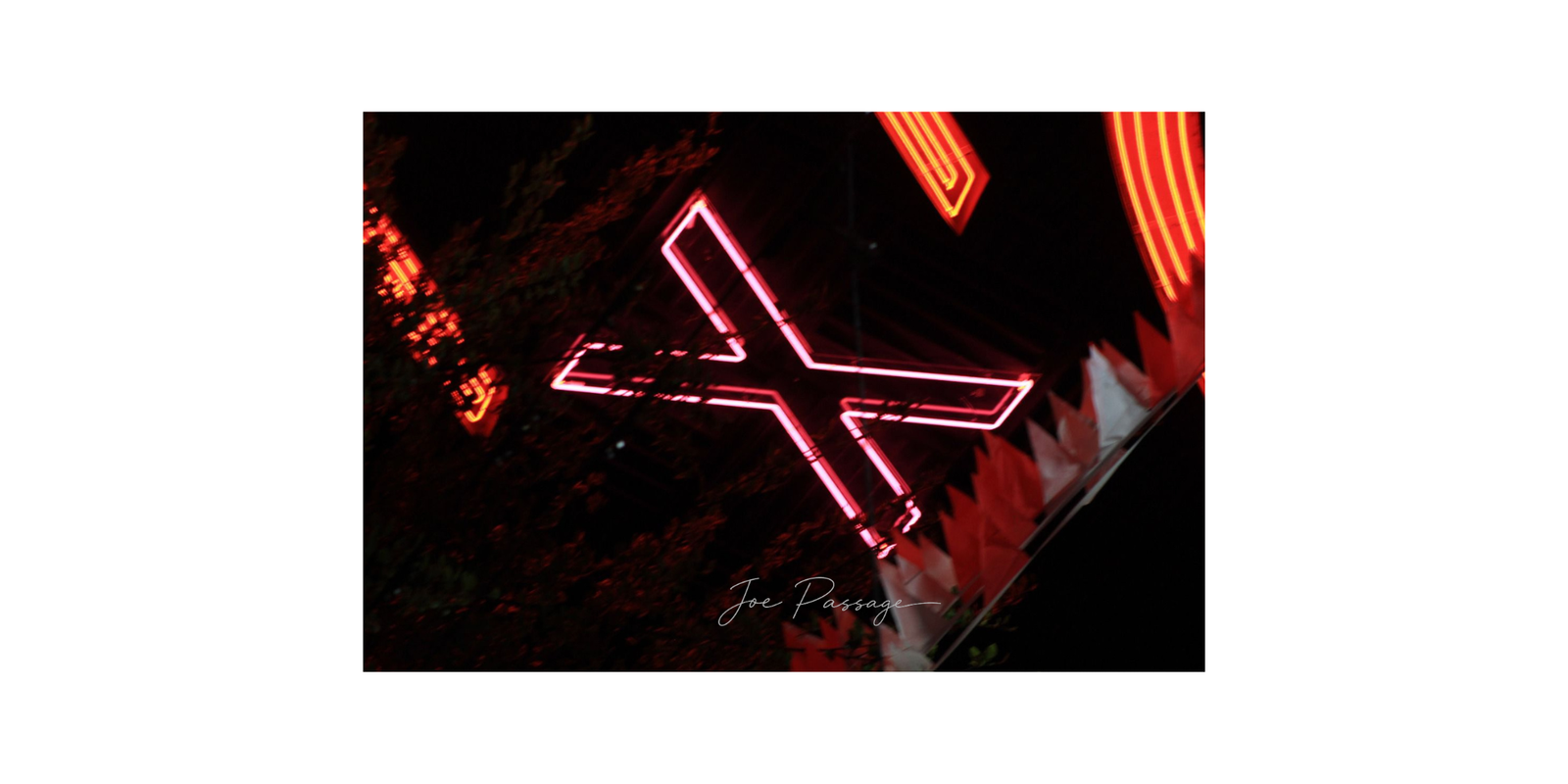 Red neon X sign photographed at night, with glowing geometric lines against a dark urban background.